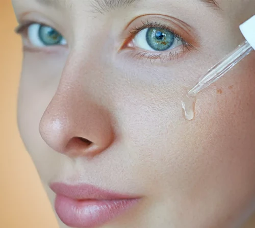 li-woman-applying-facial-serum-dropper-skincare-routine.webp