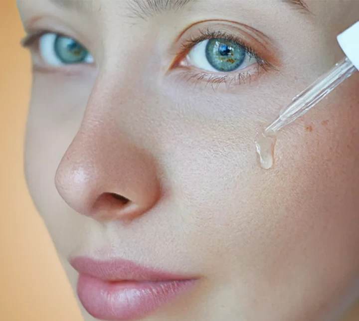 li-woman-applying-facial-serum-dropper-skincare-routine.webp